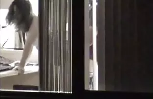 Djevojčica koja proviruje kroz prozor pribijaju čavle ispred prozora